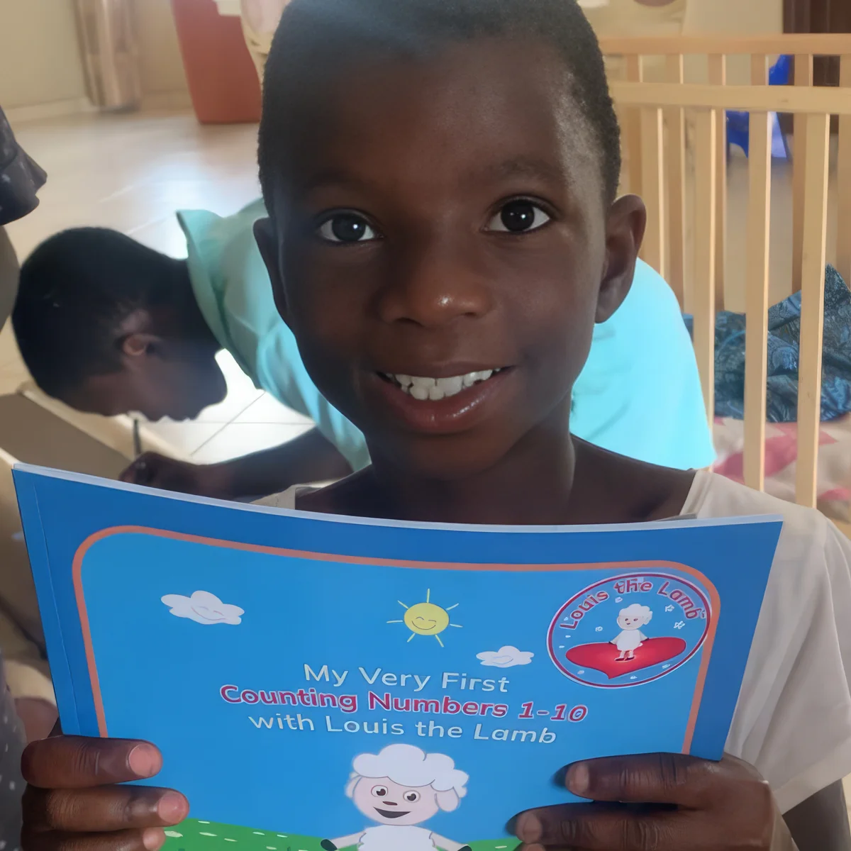 A smiling child holding a Louis the Lamb book